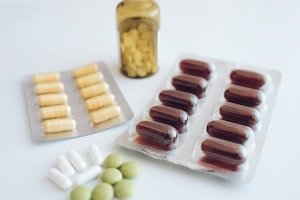 حبوب فيتامينات ومكملات غذائية على طاولة ترمز لأهمية فيتامينات الحمل مثل حمض الفوليك
